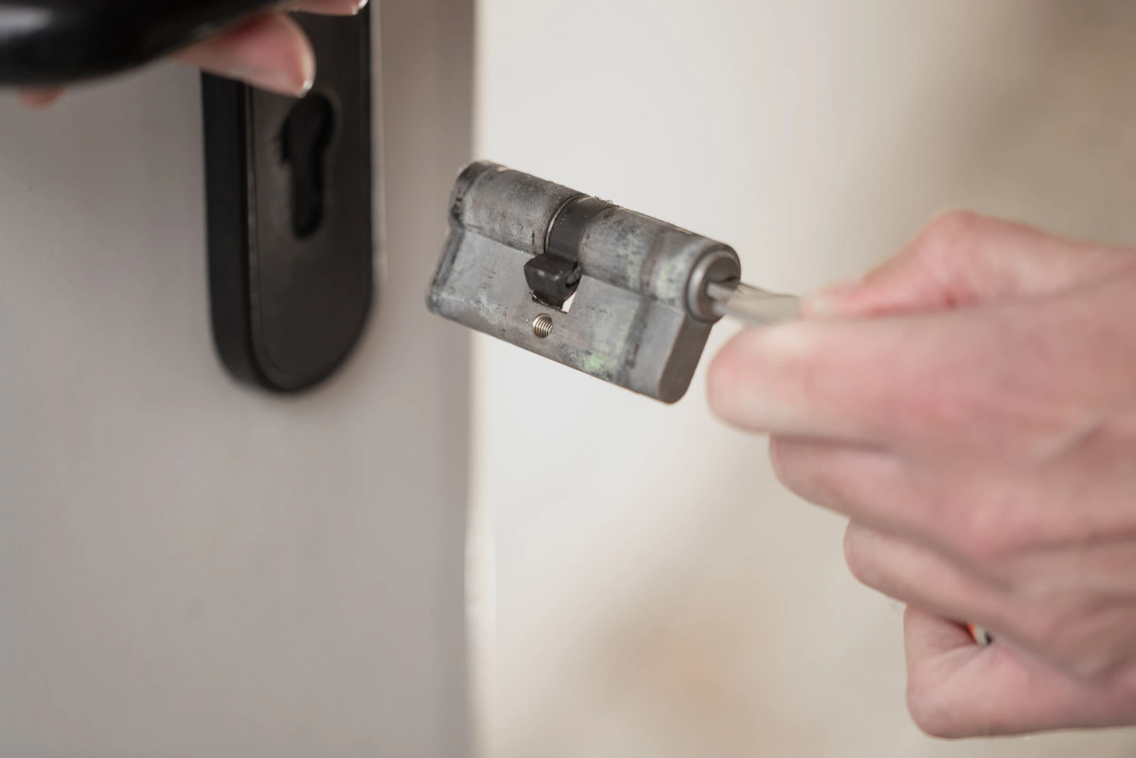 Detailansicht: Ein Monteur von MT Schlossheld hält einen ausgebauten, alten Schließzylinder nach der Türöffnung.